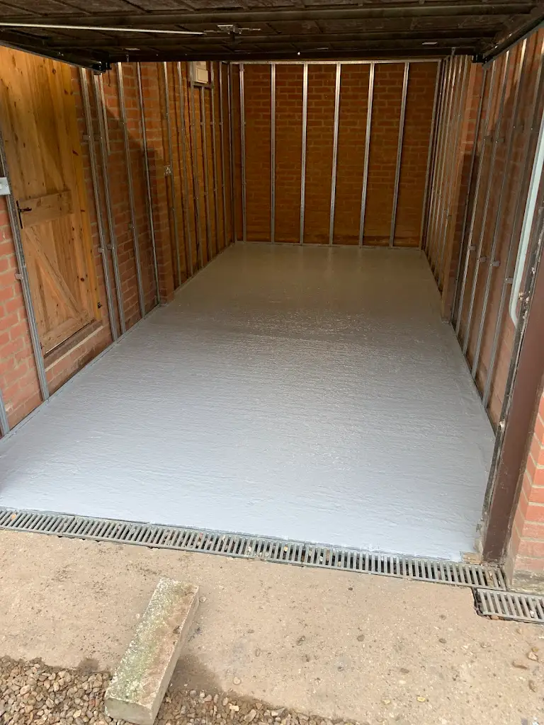 Newly finished concrete floor inside shed, smooth grey painted surface for protection