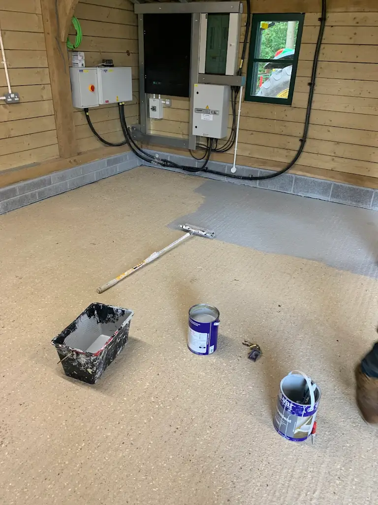 Garage floor painting process with roller and paint tins, durable coating applied neatly