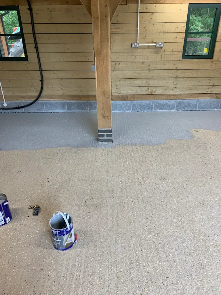 Freshly painted garage floor with tools and paint cans, smooth grey finish by professional painter.